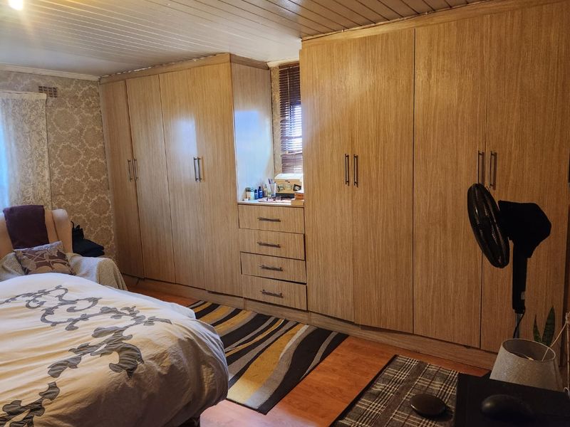 A bedroom featuring extensive built-in wooden cabinetry, laminate flooring, and a timber-paneled ceiling.