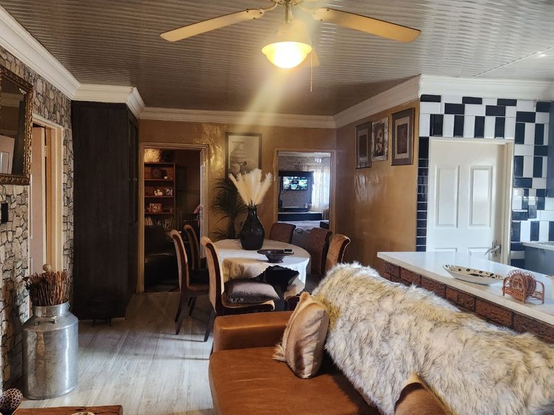 Open-plan living and dining area featuring a unique corrugated metal ceiling, stone accent wall, and a breakfast bar with checkerboard tile detailing.