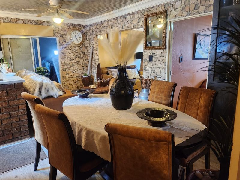 Open plan dining area featuring stone veneer wall accents, a brick breakfast bar, and a ceiling fan, connecting to adjacent living spaces.
