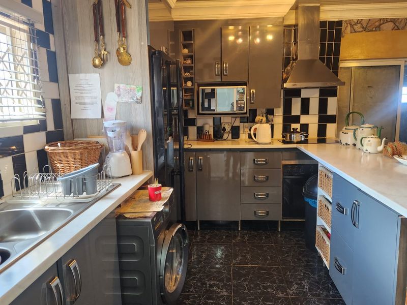 A functional kitchen featuring grey cabinetry, tiled backsplash, built-in oven, extractor fan, and tiled flooring with ample counter space.