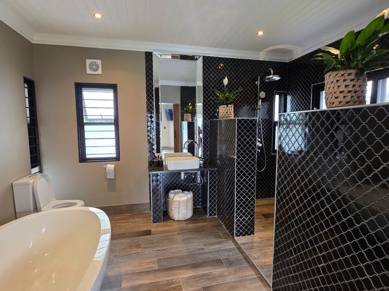 Modern bathroom featuring a freestanding bathtub, walk-in shower with decorative tiling, vessel sink, and high-quality finishes throughout.