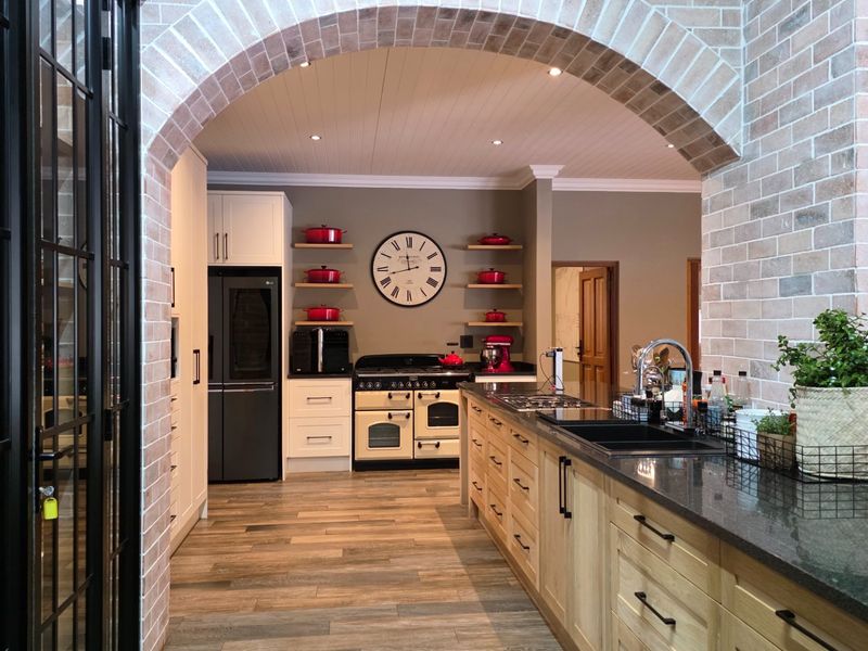 A beautifully appointed kitchen featuring a brick archway, a large central island with granite countertops, and a classic freestanding range cooker.