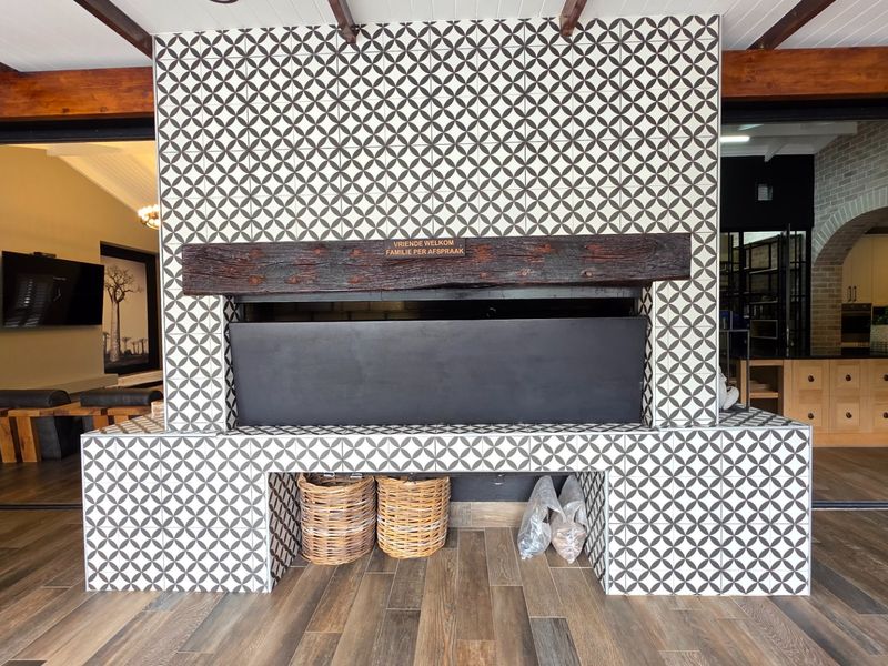 Covered patio area featuring a striking tiled built-in fireplace with a rustic timber mantelpiece and wood-look flooring.