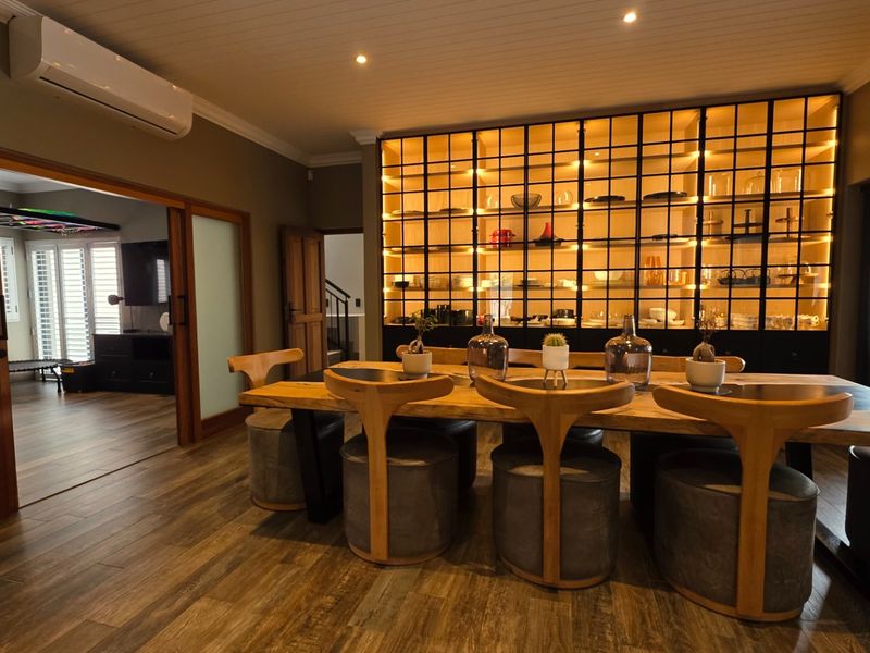 Elegant dining room featuring wood-look tile flooring, a striking built-in illuminated display cabinet, and sliding wooden doors leading to an adjacent living space.