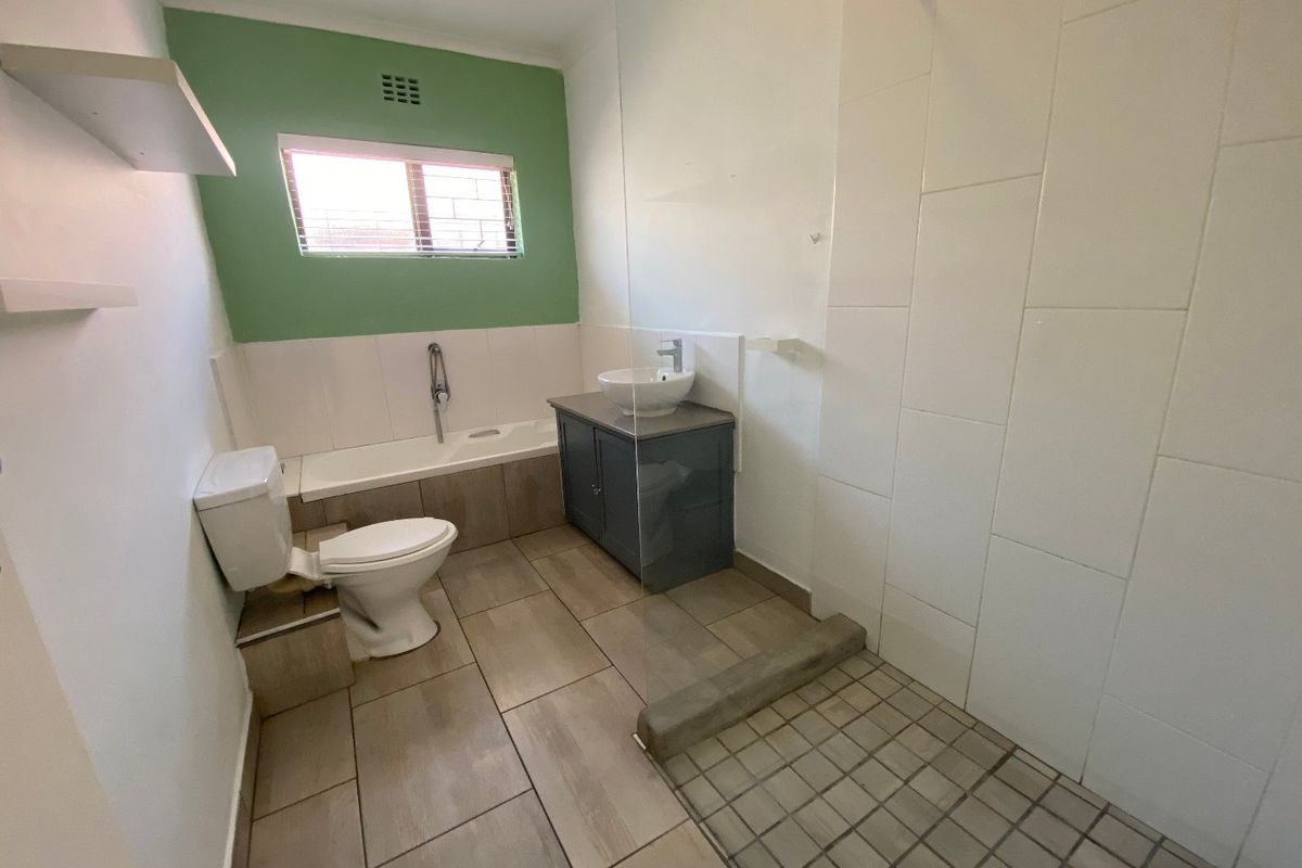 A functional bathroom featuring a built-in bathtub, a separate shower with a glass screen, a vanity with a vessel sink, and tiled flooring.