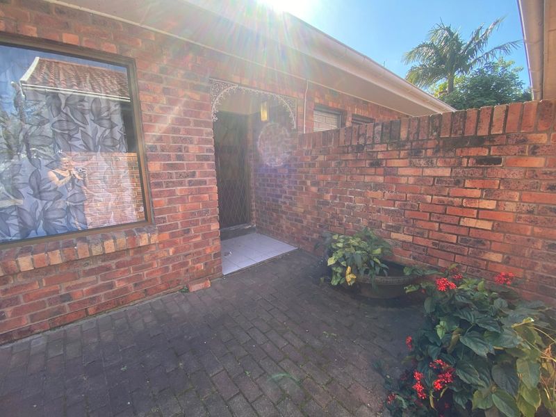 A brick-faced exterior entrance area featuring a paved courtyard, security gate, and decorative metalwork detailing.