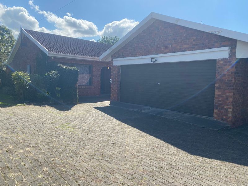 Front exterior view of a brick house featuring a double garage and a paved driveway.
