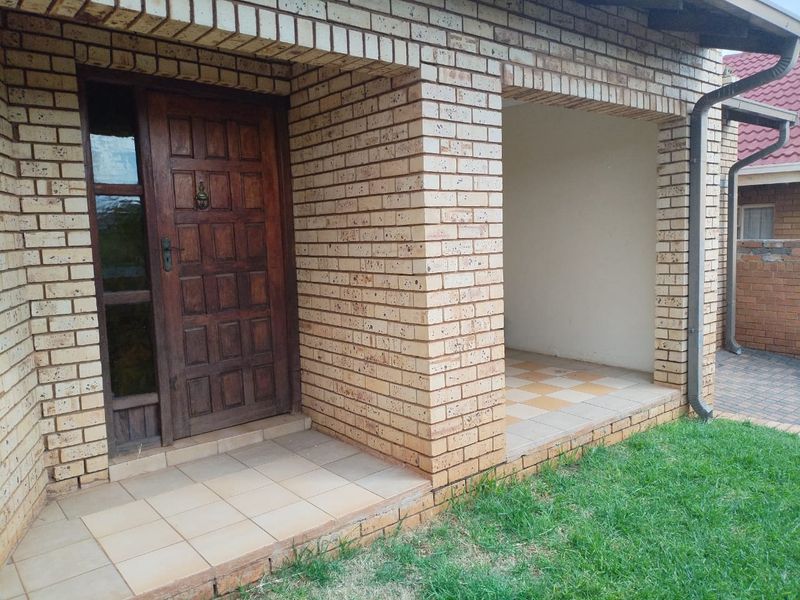 Front entrance area featuring a face brick facade, a covered tiled porch, and a traditional timber front door.