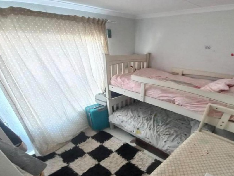 A compact bedroom featuring neutral walls, coving, and a large window with curtain rail, requiring minor cosmetic updates to improve its overall condition.