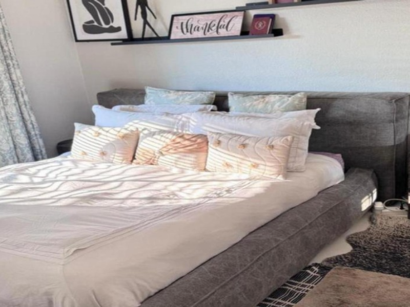 A well-maintained bedroom featuring neutral wall finishes and built-in wall shelving, providing a comfortable and functional sleeping space.