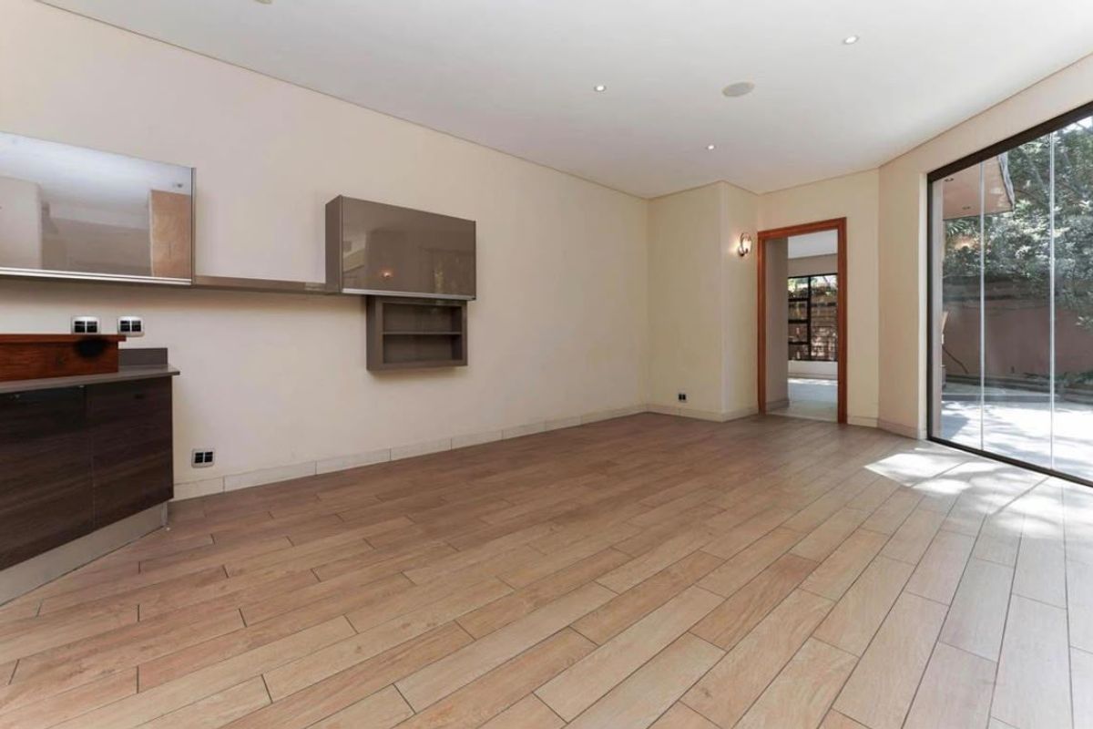 Spacious living area featuring wood-look tile flooring, recessed downlights, and large sliding glass doors providing access to the outdoor area.