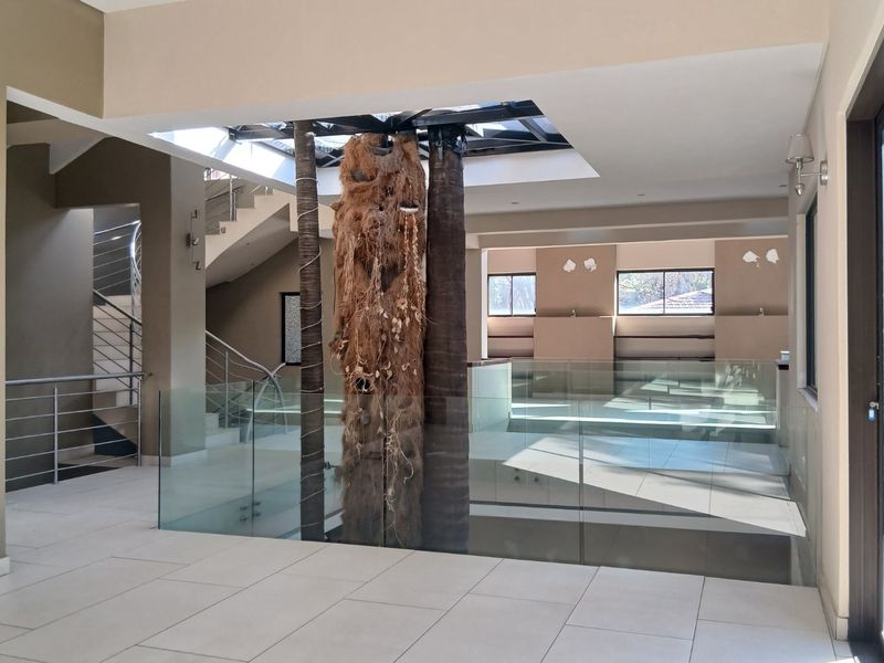 Spacious landing area featuring a central skylight, glass balustrades, and a staircase, offering an open-plan layout with modern tiled flooring.
