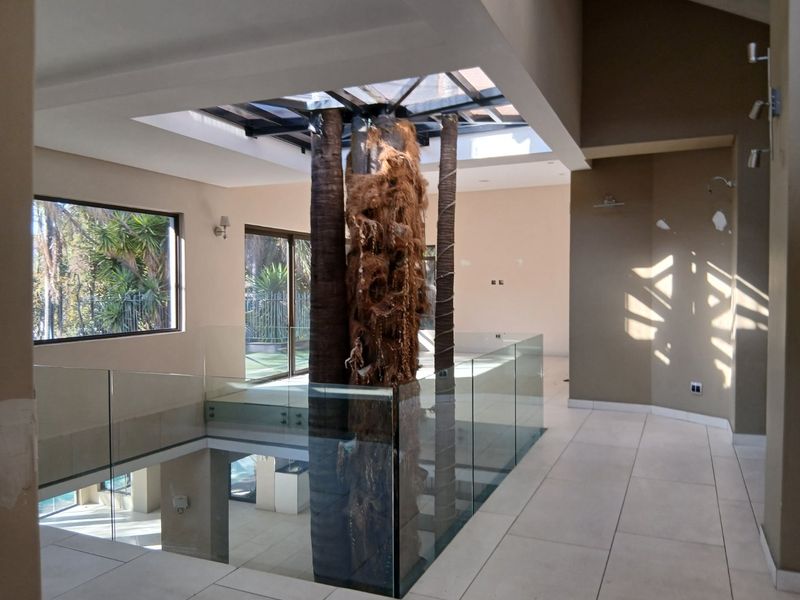 Spacious landing area featuring a central skylight, glass balustrades, and tiled flooring, offering an open and airy architectural design.