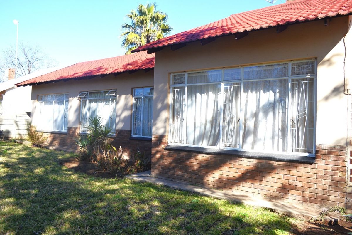 Rear view of the house featuring a red tiled roof, brick base, and windows fitted with security bars.