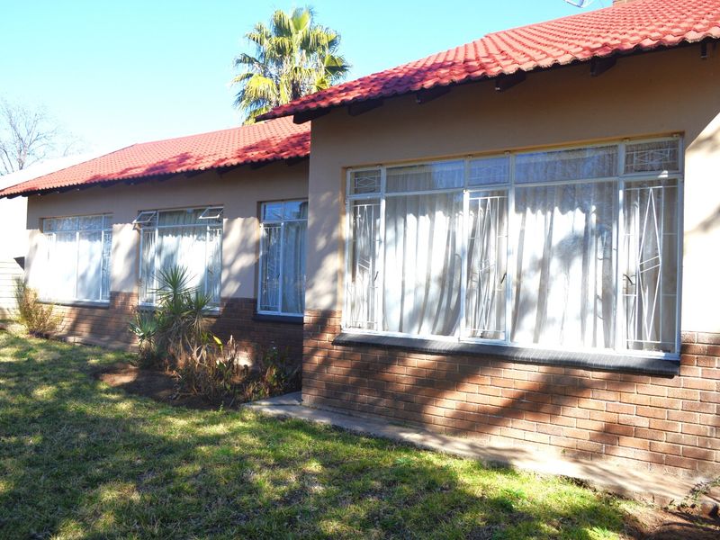 Rear view of the house featuring a red tiled roof, brick base, and windows fitted with security bars.