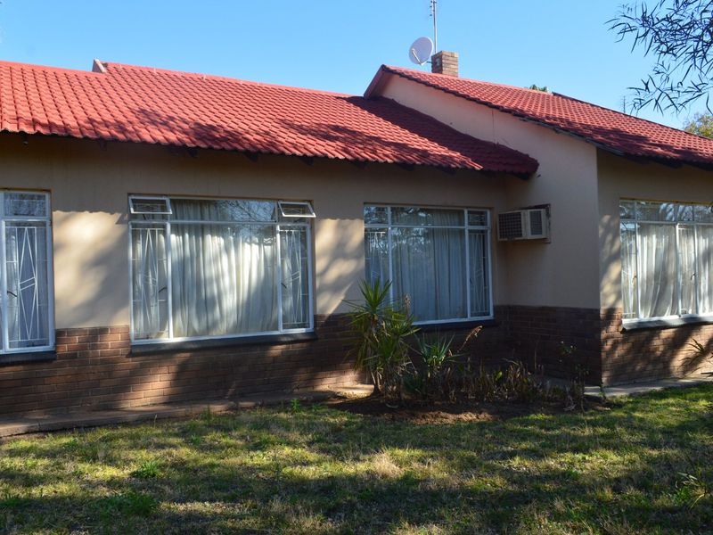 Rear view of a single-story house featuring a red tiled roof, brick base, and security bars on the windows.