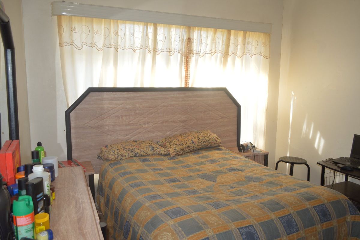 A functional bedroom featuring a window with installed curtain rails, providing natural light to the space.
