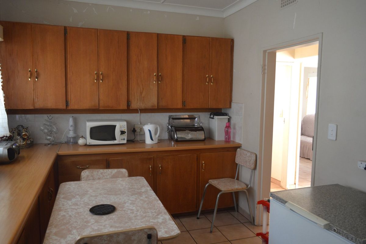 A dated kitchen featuring traditional wooden cabinetry, laminate countertops, and tiled flooring, offering significant potential for a modern renovation.