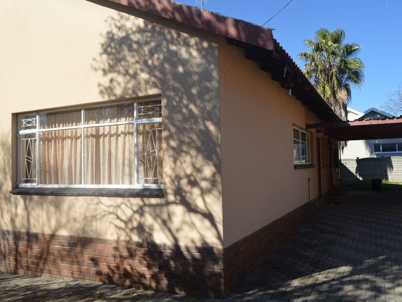 Side view of the property featuring brick paving, a metal roof, and security bars on the windows.