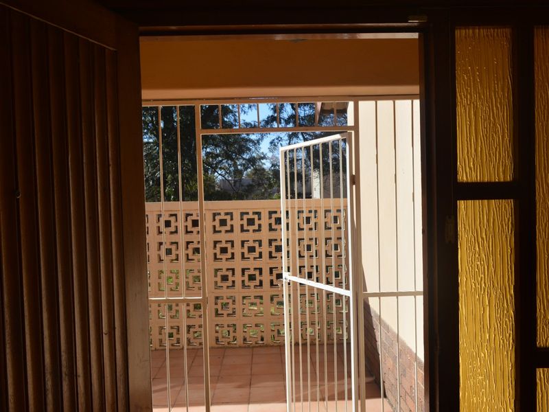A view from an interior doorway looking out onto a covered patio area featuring a decorative breeze block wall and security gate.