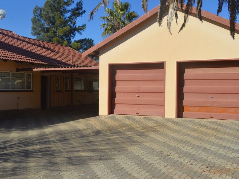 Front view of the property featuring a double garage with paved driveway and a covered entrance area.