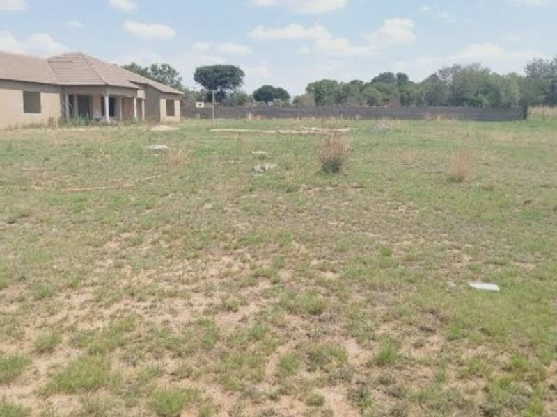 A wide view of the rear yard showing the back elevation of the house with a covered patio and surrounding perimeter wall.