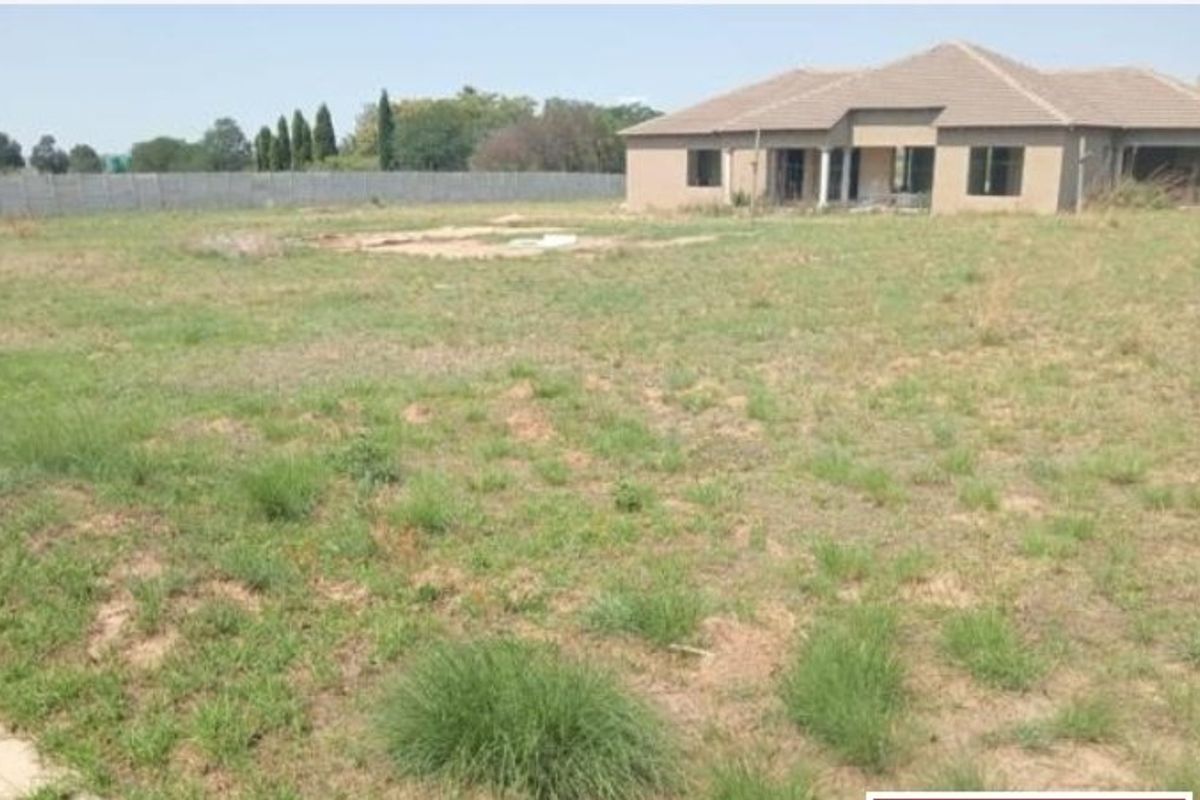 A view of the rear elevation of a farm property featuring a large undeveloped garden area and a single-story dwelling with a tiled roof.