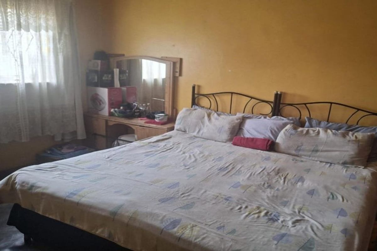 A bedroom featuring yellow painted walls and a window with curtains.