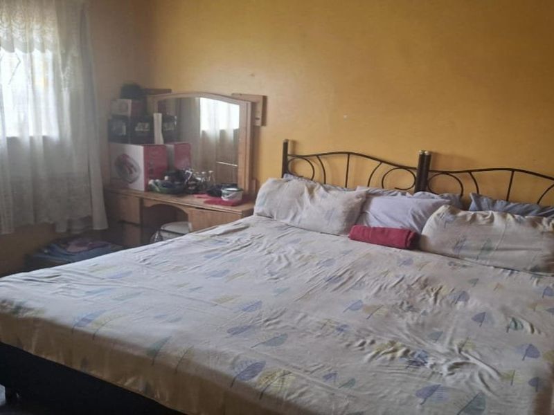 A bedroom featuring yellow painted walls and a window with curtains.