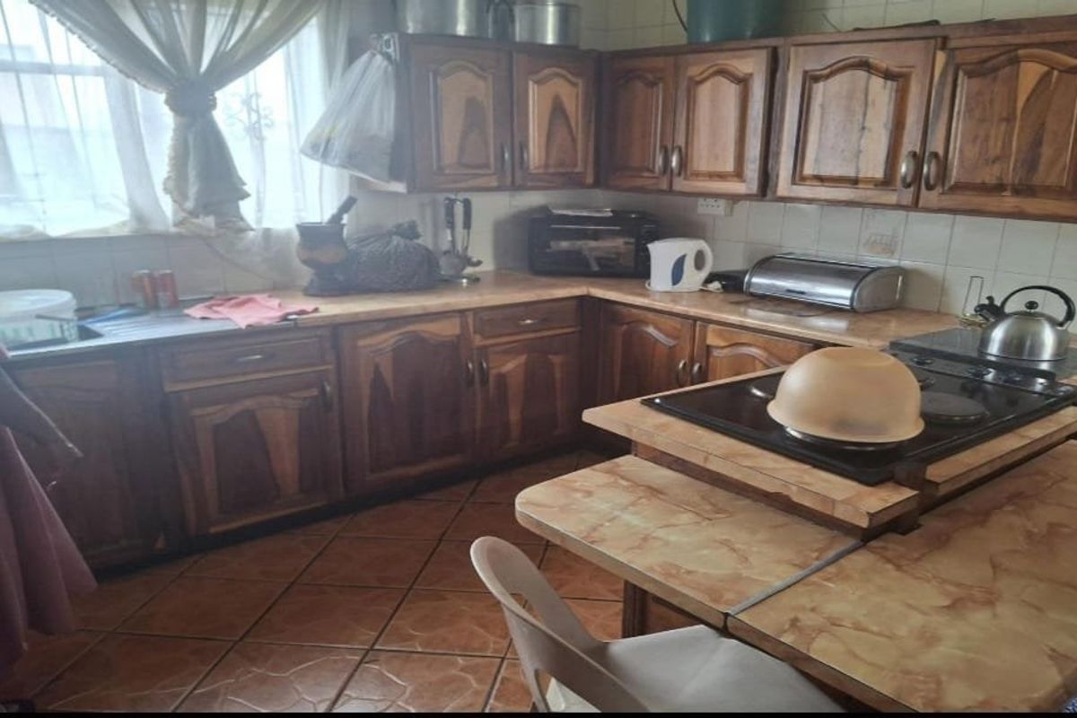 A dated kitchen featuring traditional wooden cabinetry, laminate countertops, and ceramic tile flooring, offering a functional layout with potential for modern renovation.
