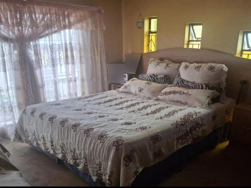 A bedroom featuring a built-in headboard and multiple small casement windows, providing natural light and a functional layout.