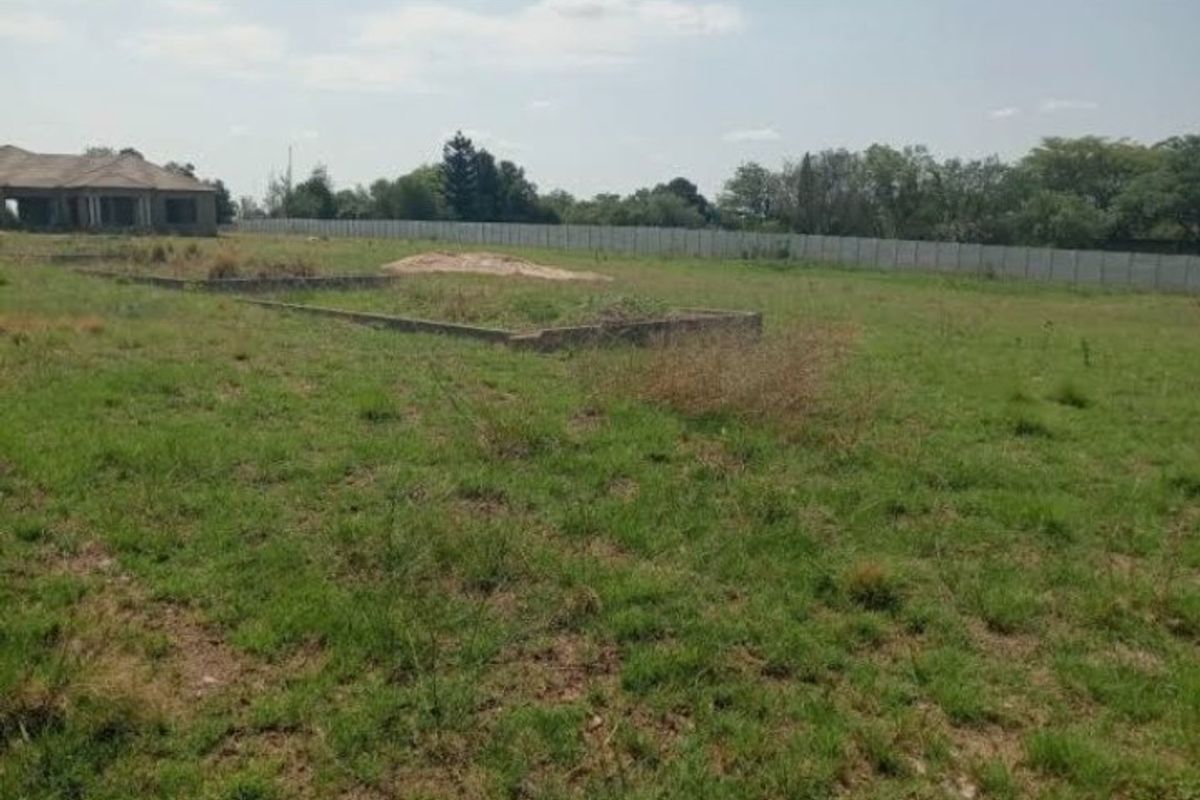 A vacant residential plot featuring a concrete perimeter wall and an existing concrete foundation slab, ready for development.
