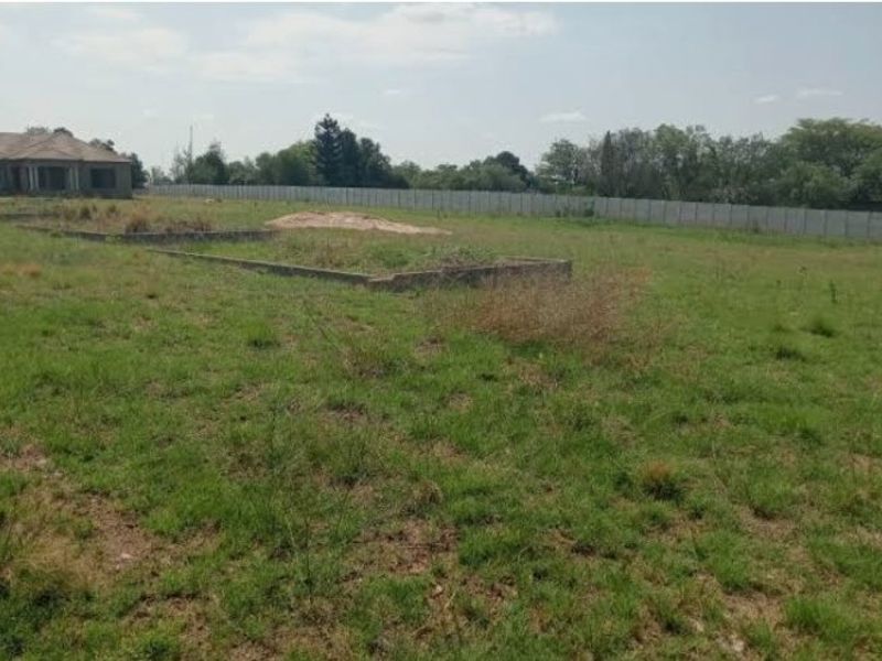 A vacant residential plot featuring a concrete perimeter wall and an existing concrete foundation slab, ready for development.