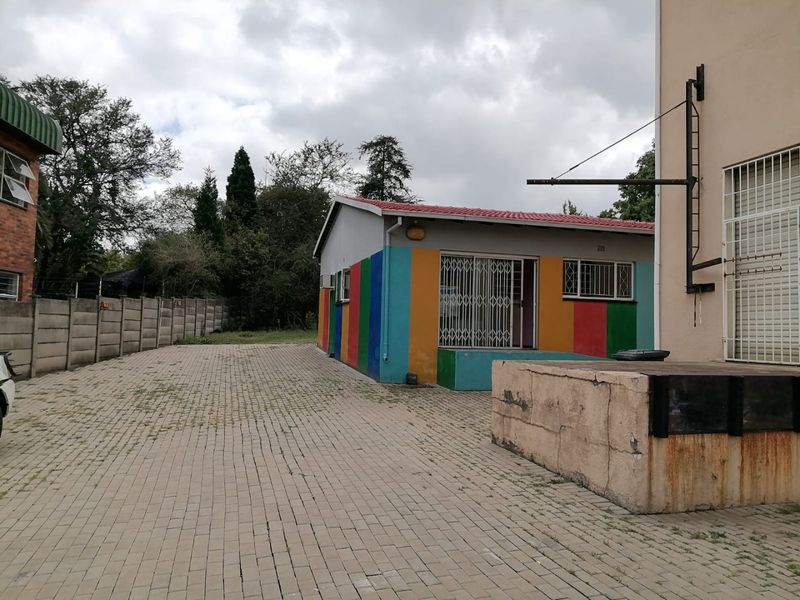 Rear exterior view of the commercial property featuring a paved yard, loading dock, and security-fitted windows and doors.