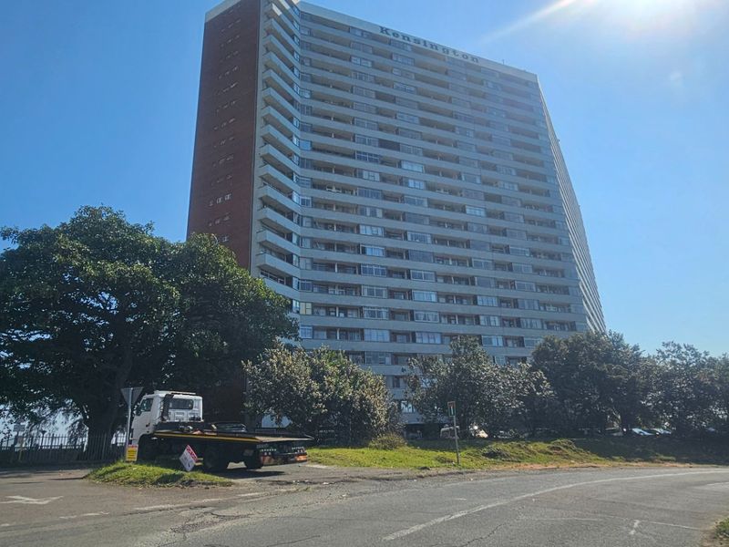 Exterior view of the Kensington high-rise apartment building, showcasing its multi-story facade with balconies and surrounding grounds.
