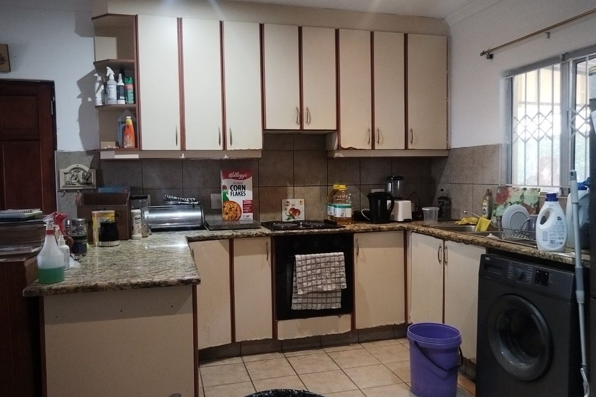 A functional kitchen featuring granite countertops, tiled backsplash, built-in cabinetry, and an integrated oven, offering potential for cosmetic updates.