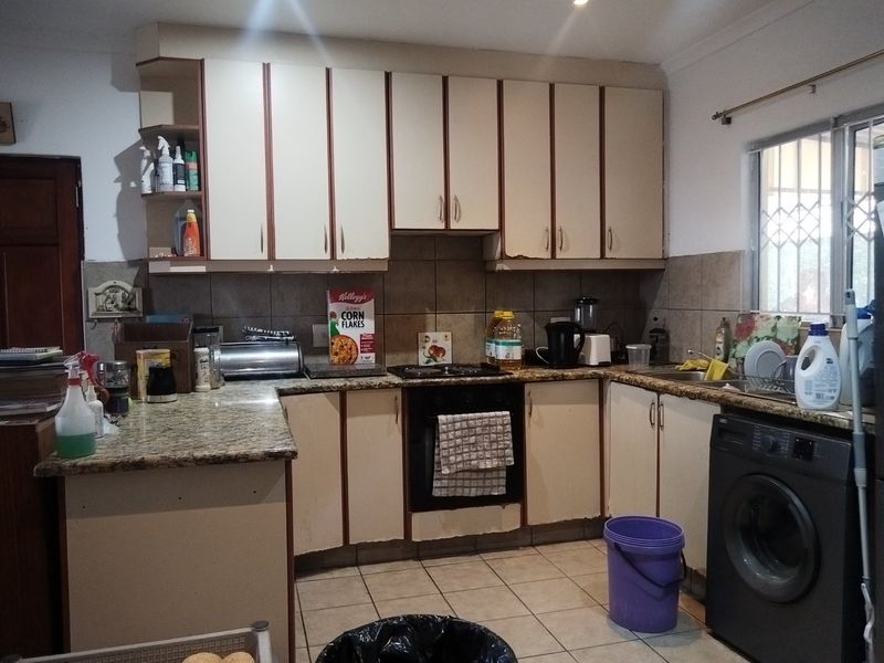 A functional kitchen featuring granite countertops, tiled backsplash, built-in cabinetry, and an integrated oven, offering potential for cosmetic updates.