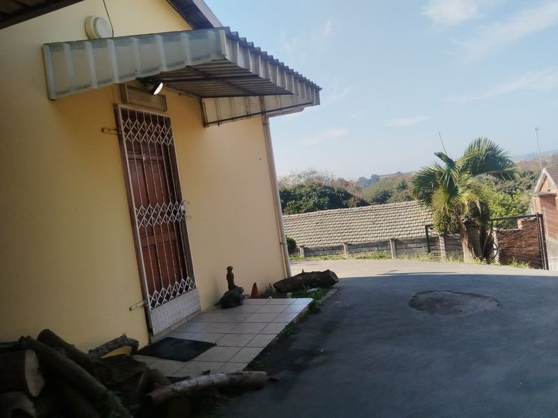 Exterior view of the property entrance featuring a security gate, tiled porch area, and paved driveway access.