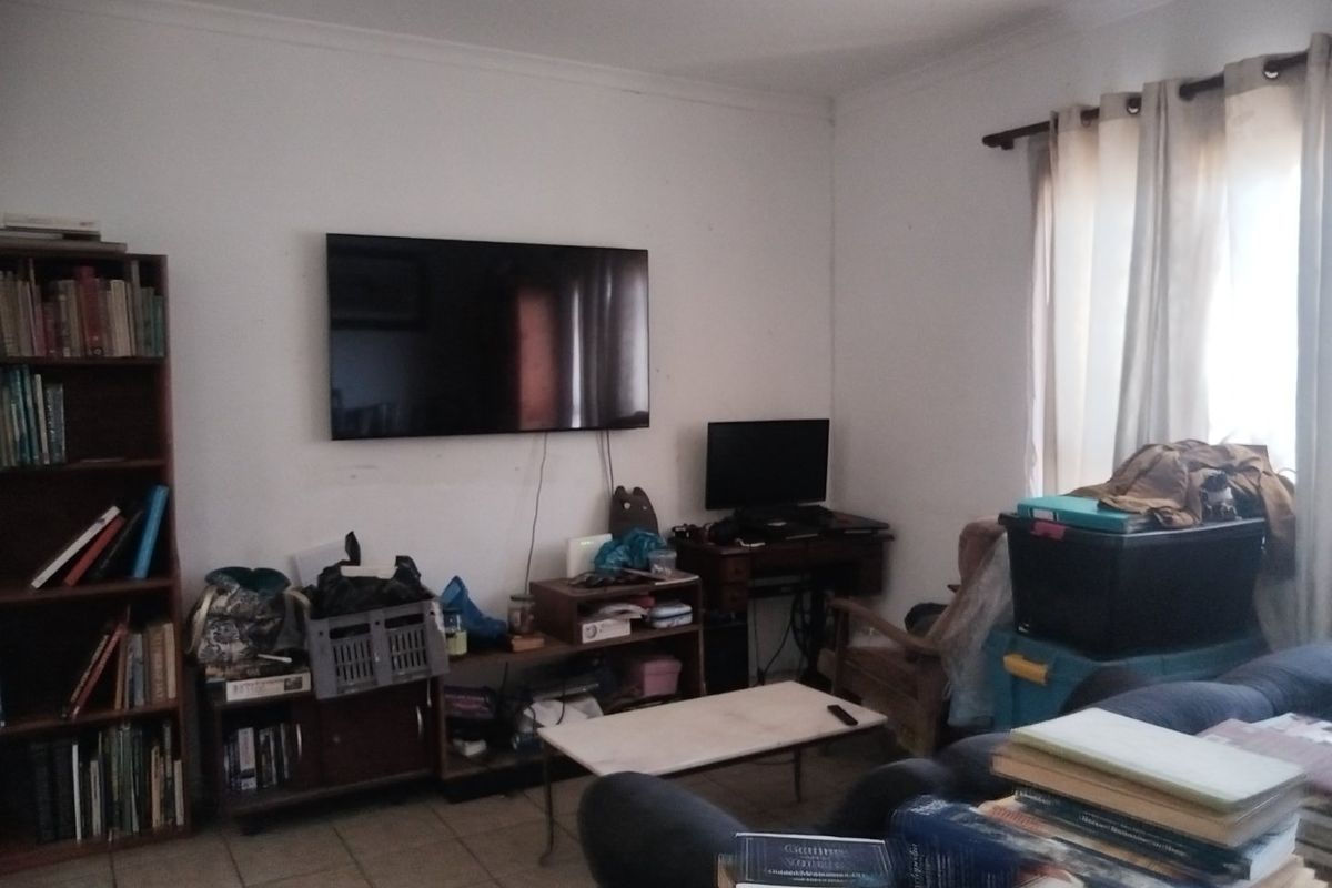 A living room featuring tiled flooring and coved ceilings, currently utilized as a multi-purpose space.