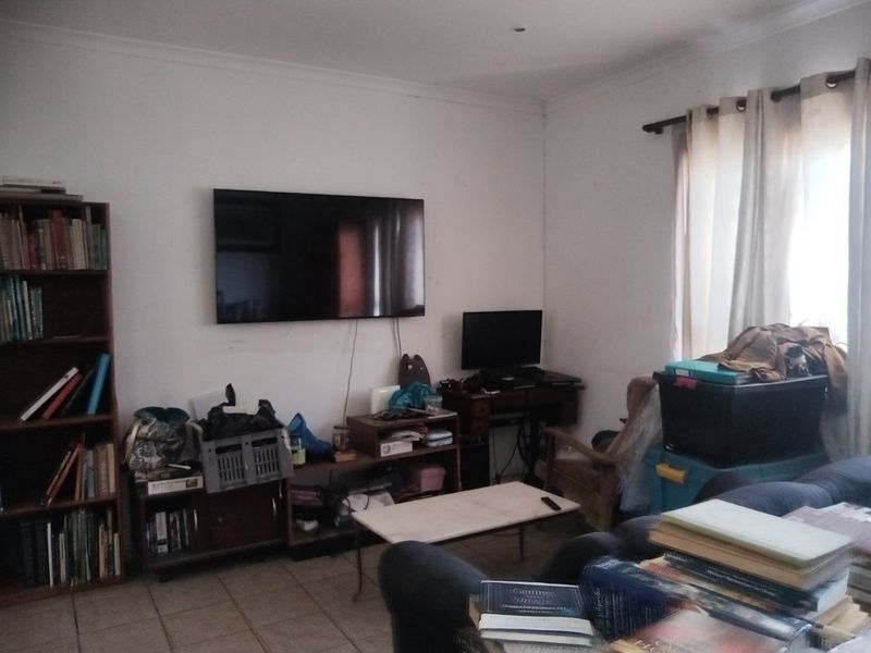 A living room featuring tiled flooring and coved ceilings, currently utilized as a multi-purpose space.