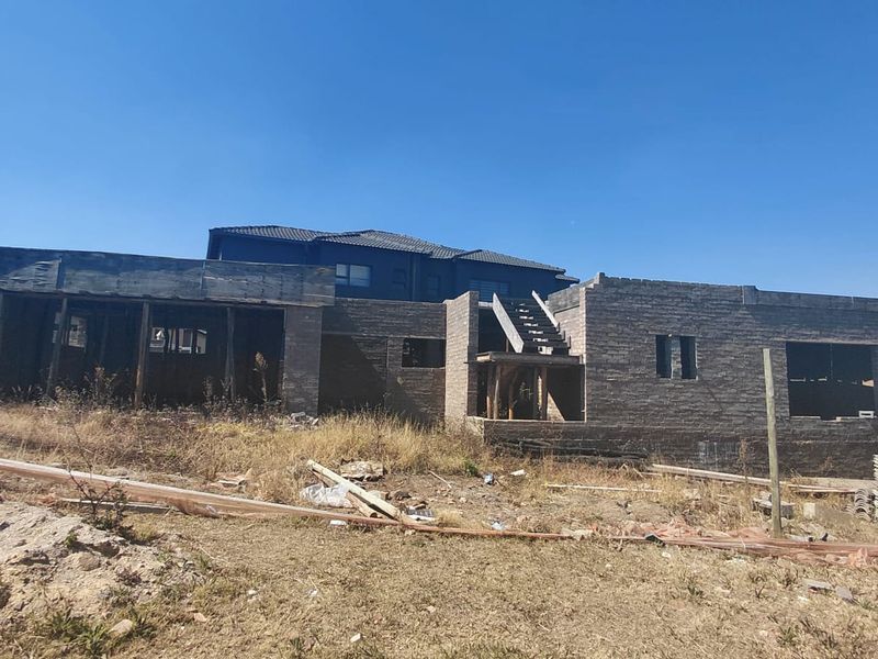 A residential property under construction featuring exposed brick masonry walls and an incomplete structural staircase on a vacant plot.