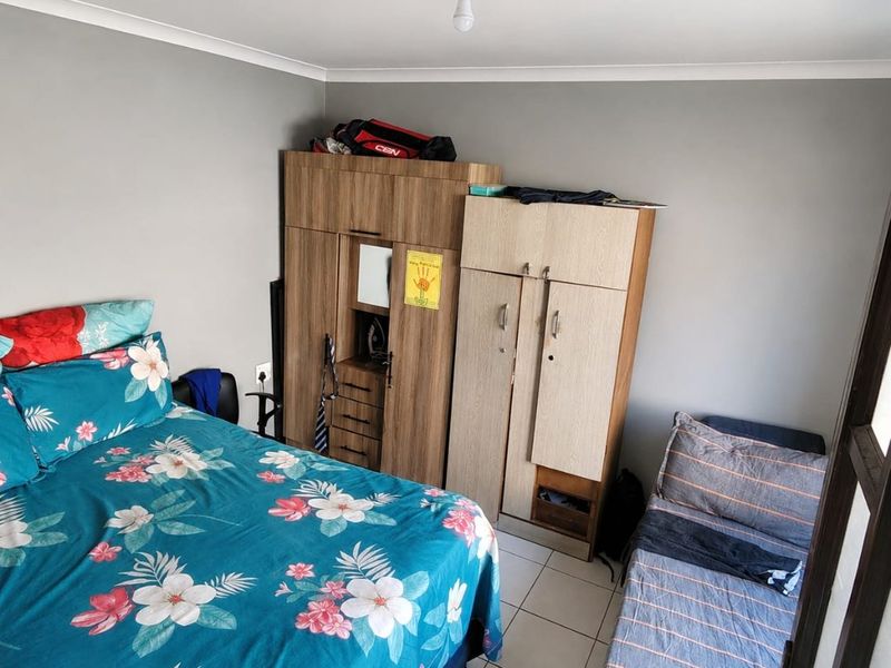A bedroom featuring tiled flooring, coved ceilings, and built-in wardrobe storage.