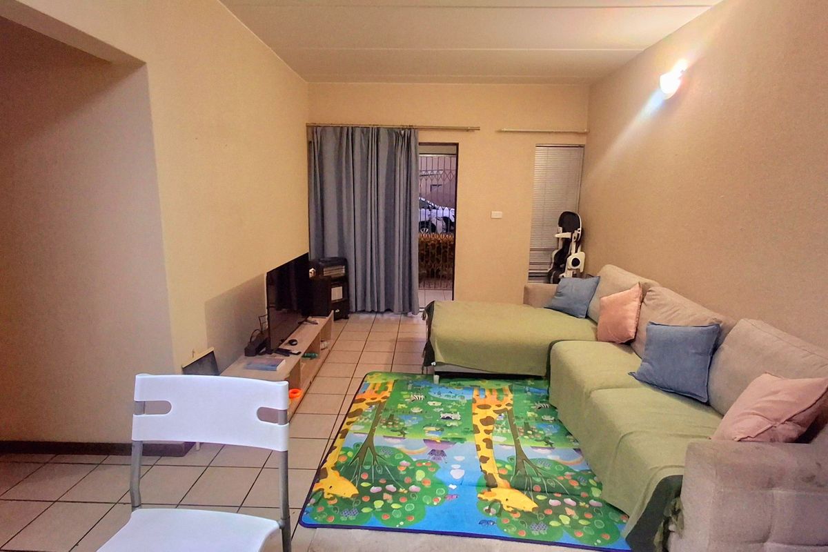 A functional living room featuring tiled flooring and a sliding door leading to an outdoor area, providing a comfortable and accessible living space.