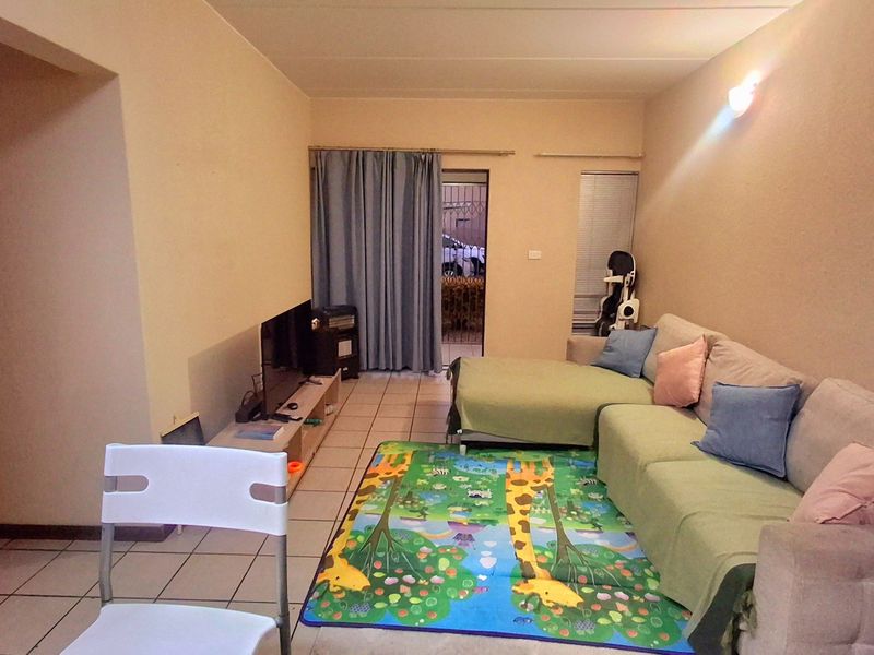 A functional living room featuring tiled flooring and a sliding door leading to an outdoor area, providing a comfortable and accessible living space.
