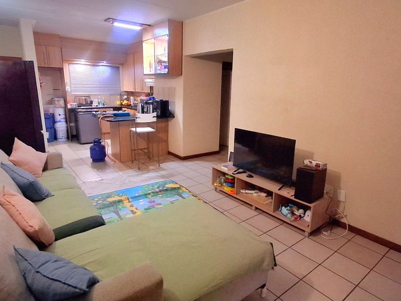 Open plan living area featuring tiled flooring and a functional kitchen with built-in cabinetry and a breakfast island.