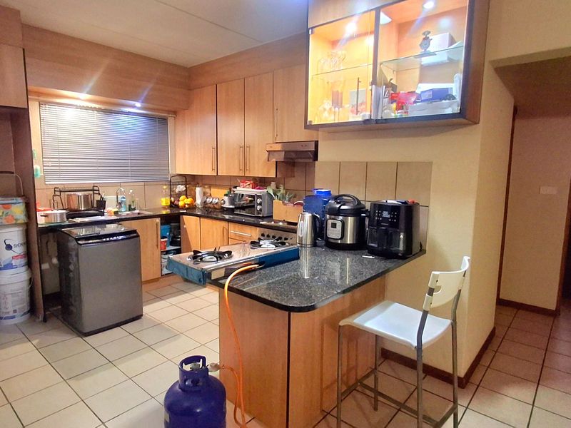 A functional kitchen featuring laminate cabinetry, granite countertops, tiled flooring, and a breakfast nook area with integrated display shelving.
