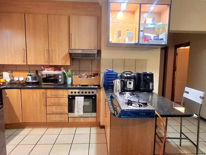 A functional kitchen featuring light wood cabinetry, dark countertops, tiled flooring, and a built-in oven with an extractor fan.