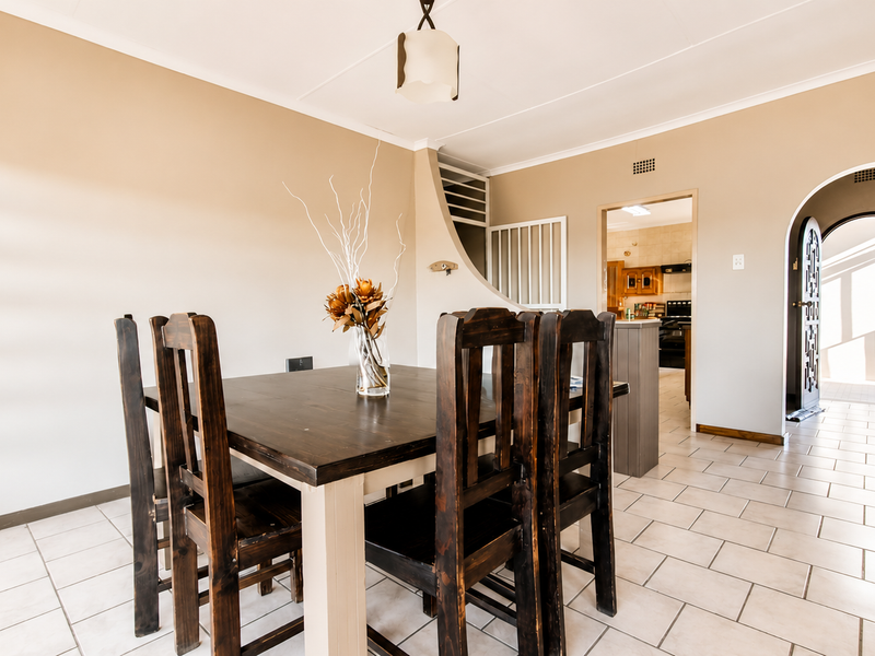 A dining room featuring tiled flooring, an arched doorway leading to the kitchen, and a central pendant light fixture.