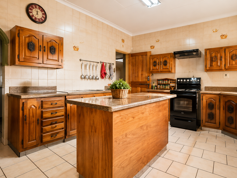 A traditional kitchen featuring wooden cabinetry, granite countertops, a central island, and tiled finishes, offering a functional layout with classic design elements.