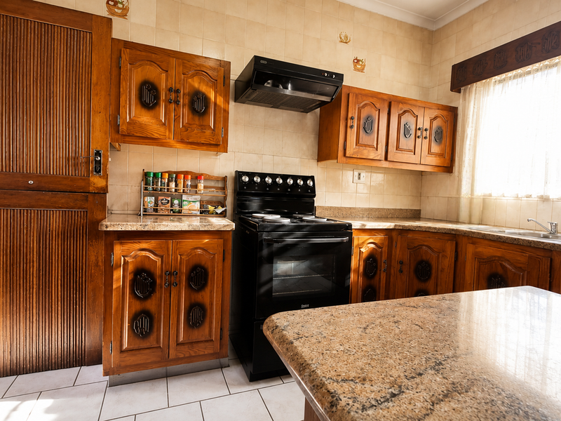 A traditional kitchen featuring wooden cabinetry, granite countertops, a freestanding oven with extractor fan, and a tiled backsplash.